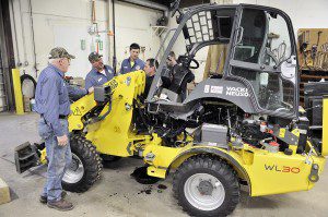Doug Dowling, center, a mechanic at Tri-County Contractors in West Springfield, explains how to change the front end of a Wacker Neuson wheel loader to a group of Southwick Department of Public Works employees Monday. The town voted to approve funding for the machine and accessories during the May 20, 2014 town meeting. (Photo by Frederick Gore)