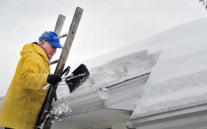A Shaker Road resident in Westfield uses a roof rake to remove snow from a February 2014 storm. (File photo by Frederick Gore)