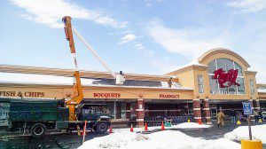 Contractors from Cotton Tree Services rope off a safety zone in the front of the Big-Y World Class Market in Southwick as workers clear the snow from the roof of the outdoor walkway Thursday afternoon. (Photo by Frederick Gore)