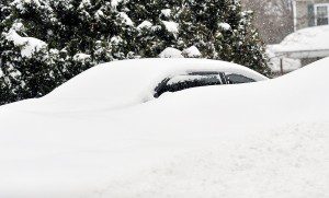 Huge snowbanks along the road cover a car parked in a driveway. (Photo by Frederick Gore)