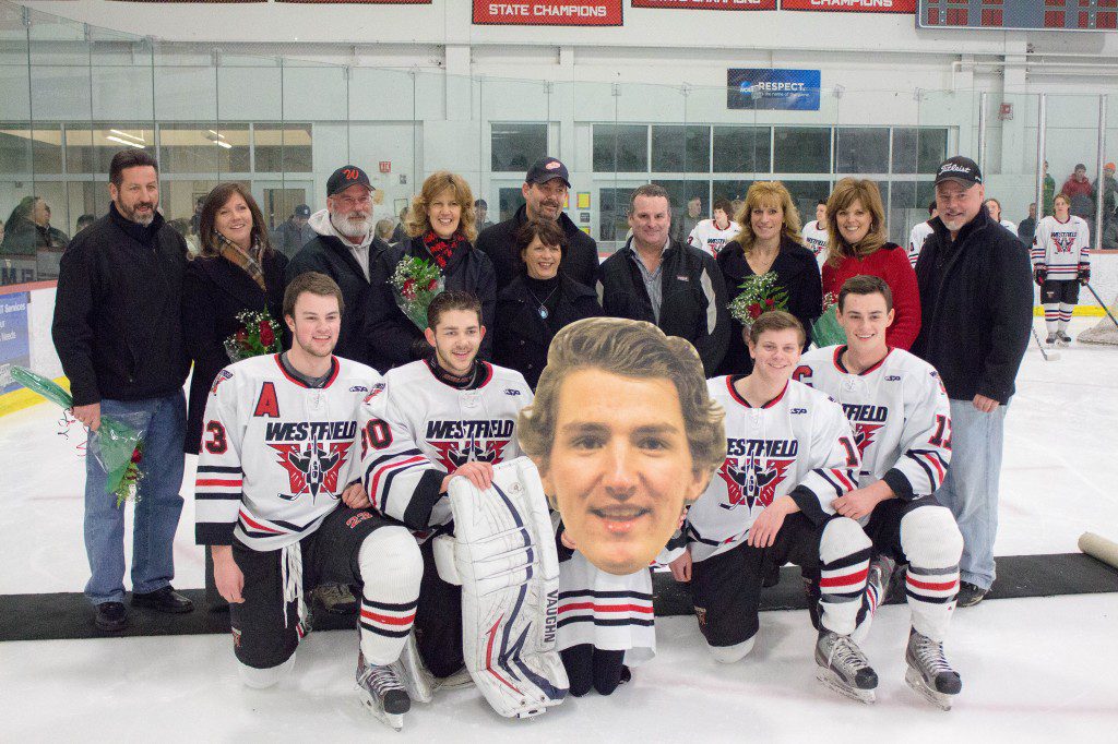 Seniors and parents pose on the ice for a photo during the Bomber Hockey Senior Night on Wednesday. Players from left to right: Assistant Captain Craig Lacey, Goalie Garrett Matthews, poster head of forward Connor Sullivan, out with an injury, Assistant Captain Samuel Evans, and Captain Christopher Sullivan. (Photo by Liam Sheehan)
