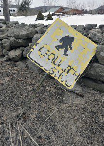 A damaged road sign rests on a stone wall on Kline Road in Southwick where drivers are warned of a Sasquatch crossing the roadway. (Photo by Frederick Gore)