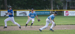 Shaun Gezotis (right) and Stefan Kroll (center) both make a move at a ground ball as a Westfield Bank baserunner eyes down the play. (Photo by Liam Sheehan)