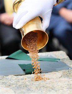 Masons pour a goblet of corn on the cornerstone as part of a ancient ceremony that was performed twice before in the 17 and 1800's, Wednesday as a time capsule is returned to the cornerstone during a ceremony at the Statehouse steps in Boston. A a set of 2015 U.S. mint coins and a silver plaque added to its contents for a future generation to discover. (Joanne Rathe/The Boston Globe via AP, Pool)