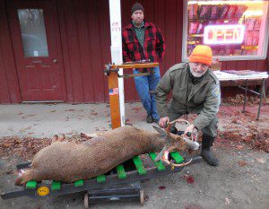 Brian Holt Hawthorne, habitat biologist with the Massachusetts Division of Fisheries and Wildlife, checks in a 111-pound deer in Huntington on the first day of shotgun season. John McDonald, rear, assisted with the check-ins. (Photo by Amy Porter)