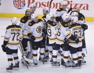 The Boston Bruins celebrate a 4-0 win over the Vancouver Canucks in an NHL hockey game Saturday, Dec. 5, 2015, in Vancouver, British Columbia. (Jonathan Hayward/The Canadian Press via AP)
