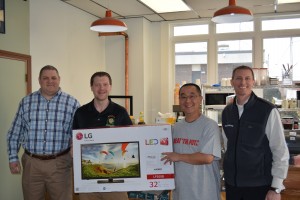 Alan Shia (second from right) accepts the flat screen TV grand prize for the 2015 Beat The Putz football contest on behalf of his father, Patrick Shia, who was the winner but was unable to attend the award presentation. Patrick Barrett (second from left) the store manager from contest sponsor Manny's TV & Appliances at 623 East Main St in the Little River Plaza hands off the grand prize. Westfield News owner Patrick Berry (far right) and sports editor Chris Putz (far left) congratulate the contestant. (Staff Photo)