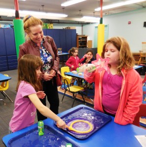 Anne Rock of Shurtleff Children's Services Fund watches as Jordan blows bubbles from the new gravity STEM kit at the Athenaeum.
