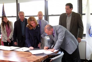 Lt. Gov. Karyn Polito looks on as Adam Dolby, chair of the Blandford Selectmen signs the Community Compact for his town. Waiting for their turn to sign are (left to right) Jane Thielen, administrative assistant and tax collector for Montgomery, Allan Vint, chair of the Middlefield Select Board, John McVeigh, selectman from Huntington, and Don Ellershaw, chair of the Chester Select Board. (Photo by Amy Porter)