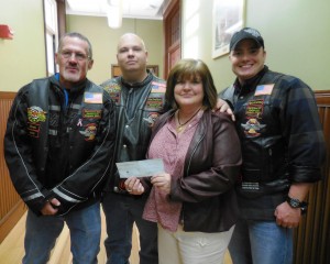 Ben Hogan, Keith Eaton and Rick Paul of the Fire & Iron Firefighters motorcycle club present a $500 check to Fort Mill Principal Joanne Hentnick at the School Commitee meeting. (Photo by Amy Porter)