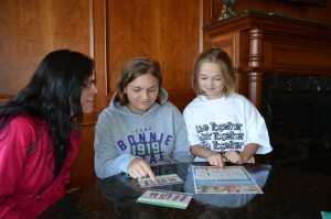 Jacqueline Senez and her daughters, Brienne and Nathalie look over summer camp options offered by Girl Scouts of Central and Western Massachusetts. A research study affirms the overwhelming benefits of outdoor experiences for girls.