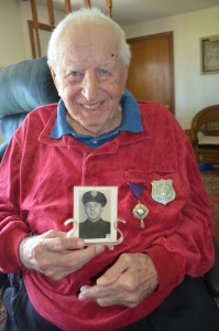 Southwick resident Stephen Fedus, Jr., now at 95, holds a photograph from his days walking the beat with the West Hartford Police Department. He recently received the department's Police Cross which he is wearing next to his badge from 1948.