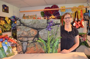 Fabric artist Dawn Allen of Westfield, seen in her studio, holds one of her pieces titled "Stonewall with Iris" that will be a part of the upcoming exhibition - "Irma and Doris Go Wine Tasting" - at the Black Birch Vineyard in Southampton.
