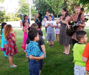 Students from the Newcomer's Program at Highland Elementary School practice their song outside before entertaining the School Committee on Tuesday. (Photo by Amy Porter)