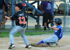 Westfied's Topher Halbert slides past Belchertown pitcher Jake Waller at home plate in a district tournament pool play game for 7-9 year-old Little Leaguers Tuesday night at Ralph E. Sanville Field. (Photo by Kellie Adam)