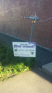 A Whip City Fiber sign with a digital antenna above it. 