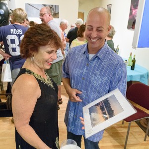 Photographer Vinny Caruso (r) shows a piece to Carol Saltus at the Rinnova Art Gallery during the recent Men & Metal art exhibit (photo by Marc St. Onge).