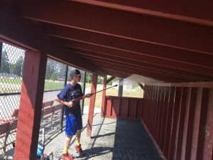 A volunteer powerwashes a dugout before a game.