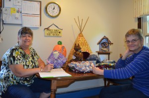 Jane Welch and Gail Cortis are coordinating logistics for the Artisans and Crafters for Hunger Fall Craft Fair. In the background are some of the unique items that will be offered for sale - birdhouses, Tee-Pees for cats, seasonal ceramics, and fleece blankets.