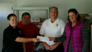Sally Munson, Chief Anderson, Bishop, and Select Board Clerk Joe Deedy are seen with the check that was from the money raised that went towards the food pantry. (Photo from Jessica Bishop)