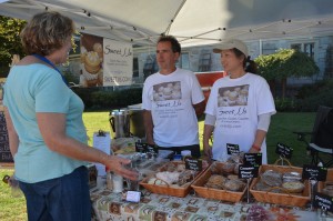 Deborah Randzio, market manager for the Westfield Farmers' Market, on left, chats with Jay Park, on right, owner of Sweet JJs. On Thursday, Park was joined by her husband John Reuss who was assisting with selling delectable offerings.