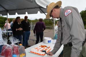 Park ranger Colin Monkiewicz of Montgomery cuts a special cake to mark the 50th anniversary of Littleville Lake and the 75th anniversary of Knightville Dam.