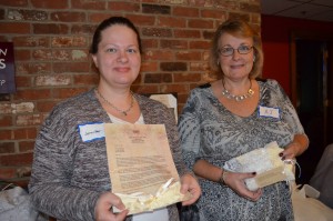 Jennifer Truscott displays the letter and swatch of fabric that is given to each person who donates a wedding gown for the Angel Babies Project, and Anne Joy show the tag that accompanies each unique garment that is given to the parents who lost a child in infancy.