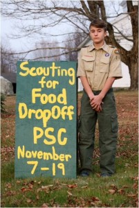 Cole Duval, a member of Boy Scout Troop 114, is seen with a sign indicating food drop off dates (photo submitted).