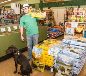 Sean Berube stocks the dog food under Reilly’s watchful eye (Photo by Lynn Boscher)